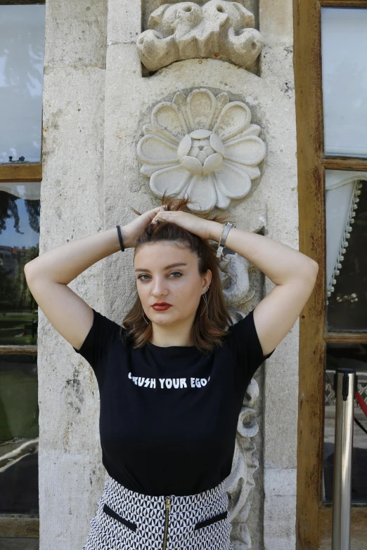 a woman standing next to a wall wearing a black shirt