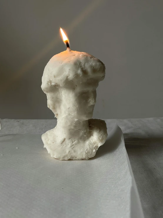 a candle with a plaster head sitting on it