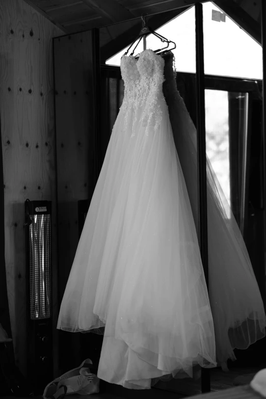 the wedding dress is hanging in the window