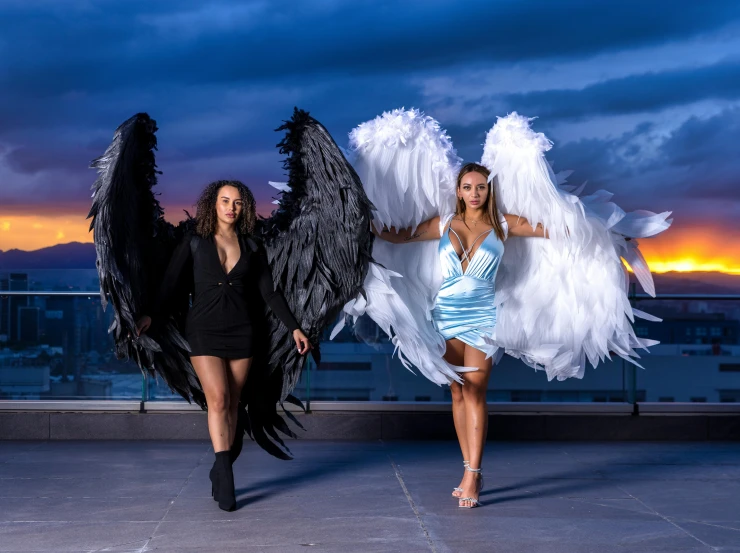 two women wearing angel wings and one holding a large white object