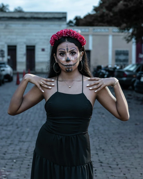 a woman in black dress holding her hands over her face with red flowers on her head