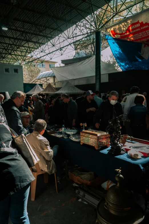 people are standing around a table that has many different things