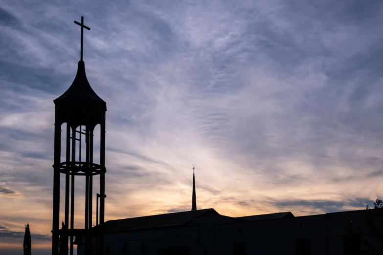 a dark clock tower under a cloudy sky