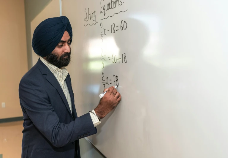 a man writing on a whiteboard with numbers and letters written in arabic