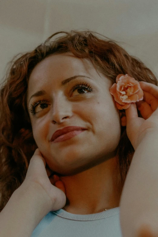 a young woman holds a flower in her hair