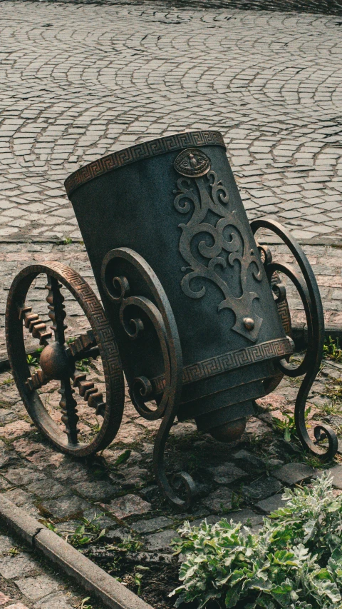 a black barrel has been placed on top of a cobblestone ground