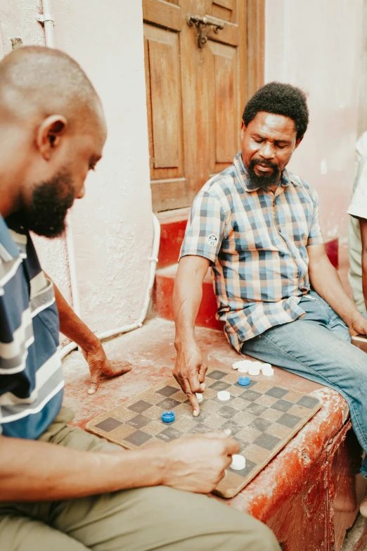 three men sitting outside playing a board game