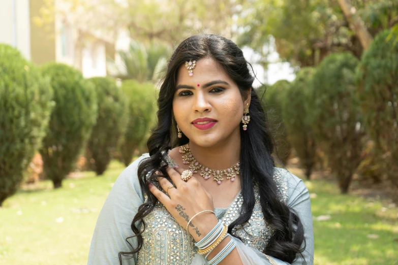 a woman in a dress and jewellery standing outside