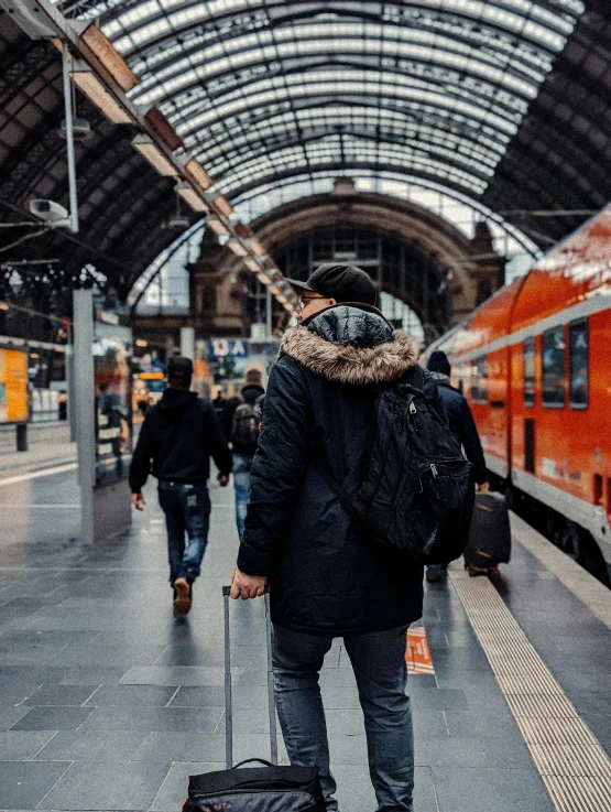 man in winter clothes carrying a bag at the train station