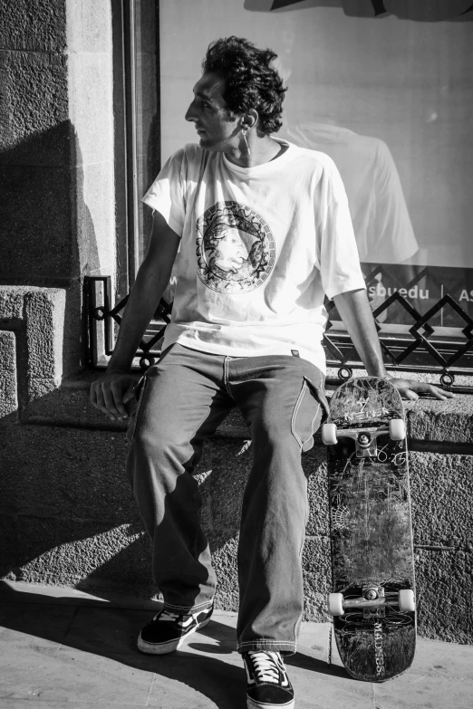 the boy sits on the curb with his skateboard