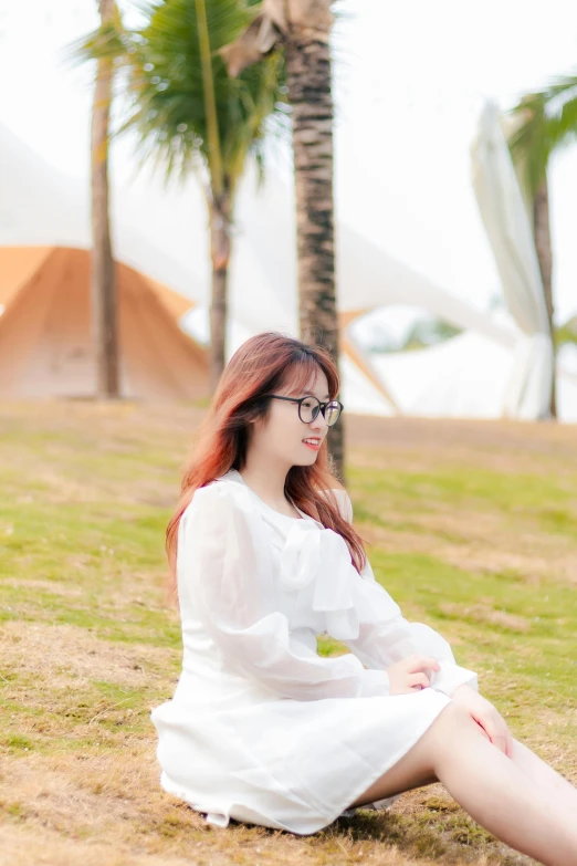 a woman wearing a white dress is sitting in the grass