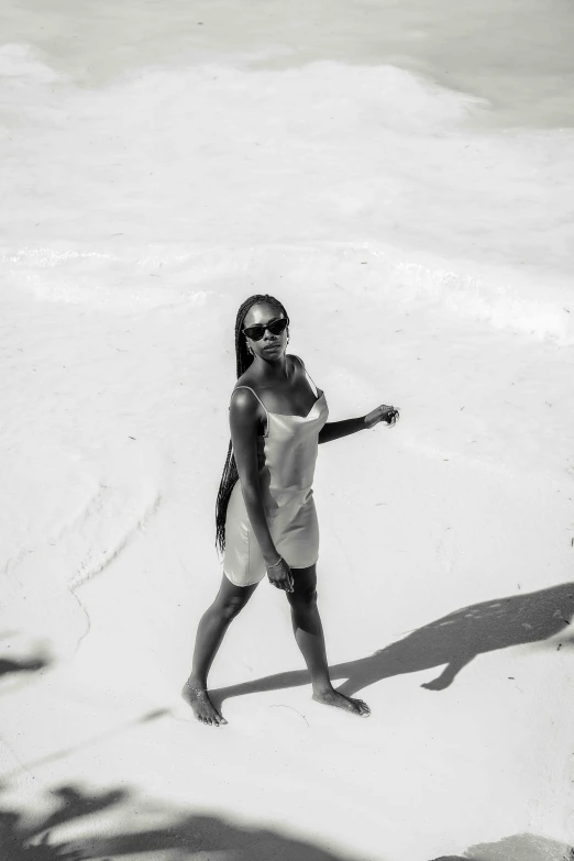 a woman wearing sun glasses standing on top of a snow covered beach