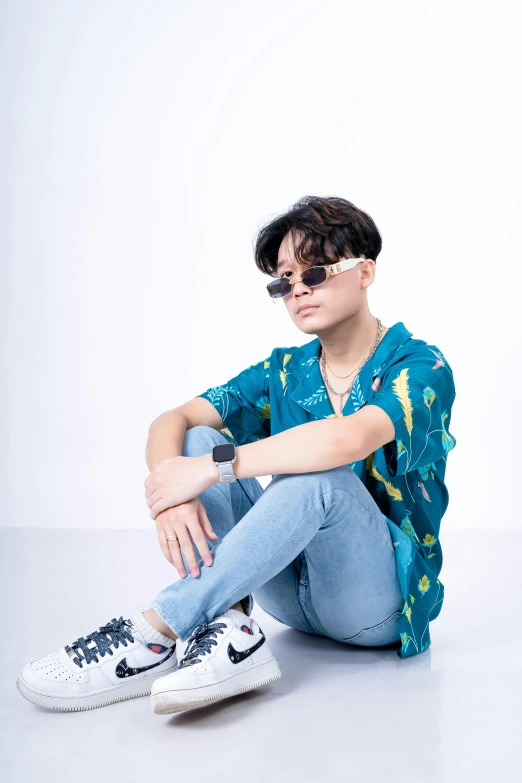 a boy sitting on the ground in white sneakers