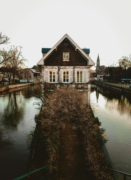 a house is seen by some water and trees