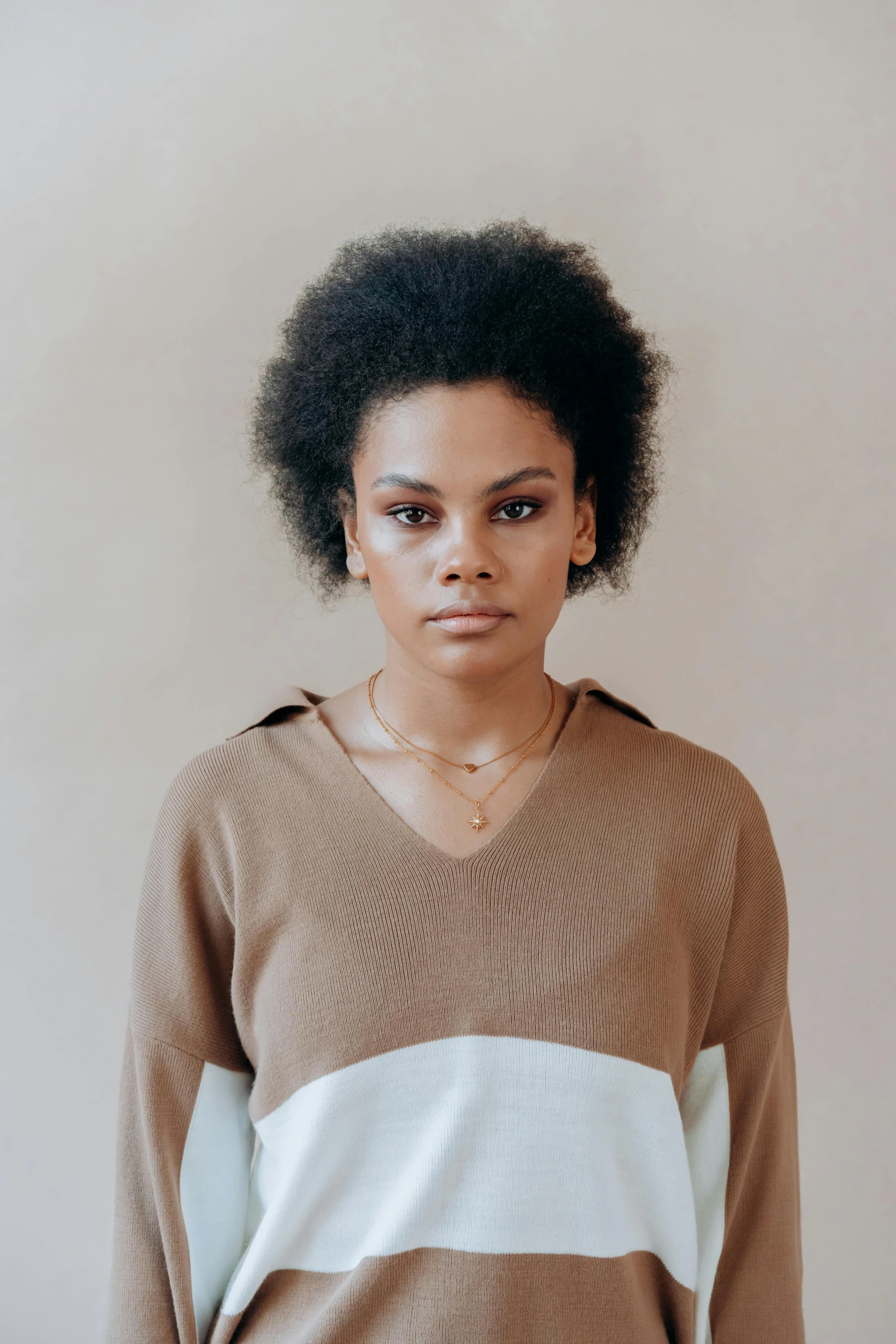 a woman wearing a sweater standing in front of a wall