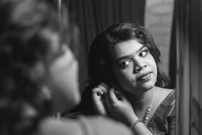 woman with hand on ear staring at mirror