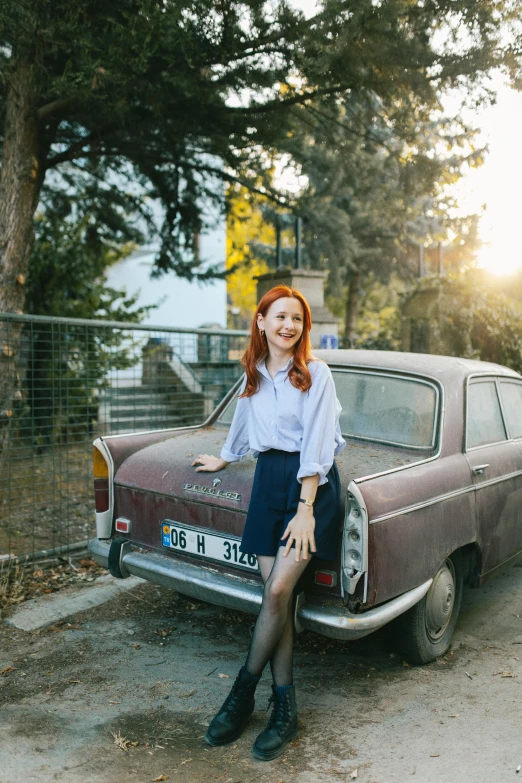 a young woman posing next to a vintage car