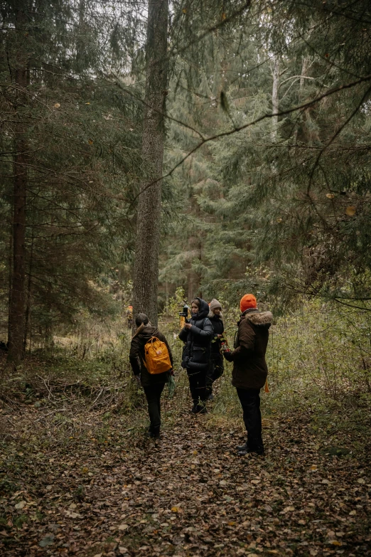 group of people walking through a forest with backpacks