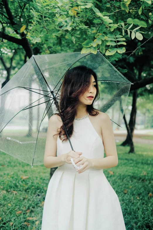 a beautiful young woman wearing a dress holding an umbrella