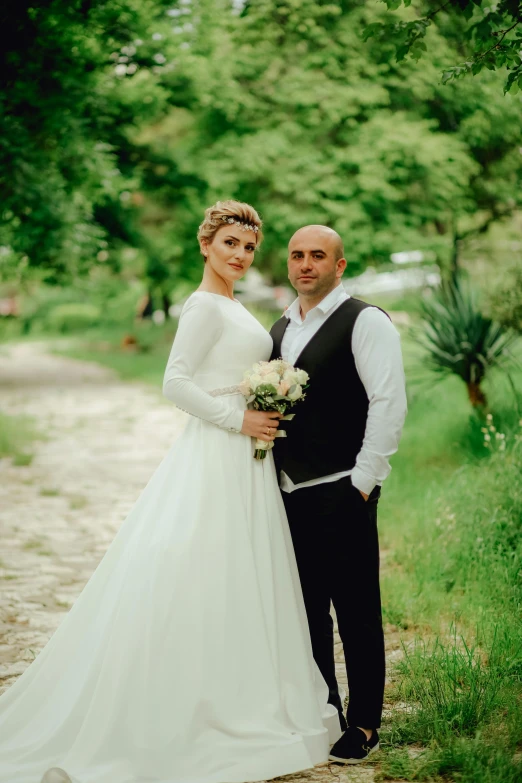 two people in white and black clothes stand together in a wooded area