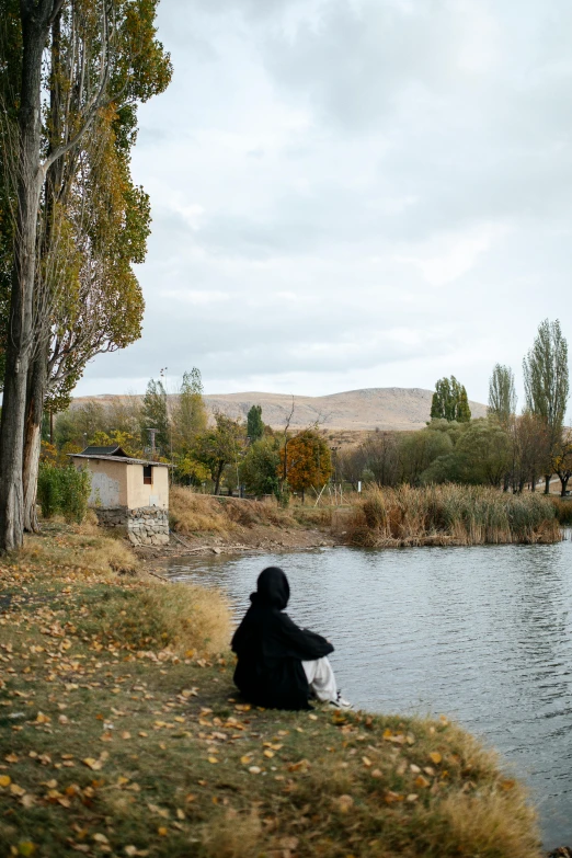 a person sitting on the ground by a body of water