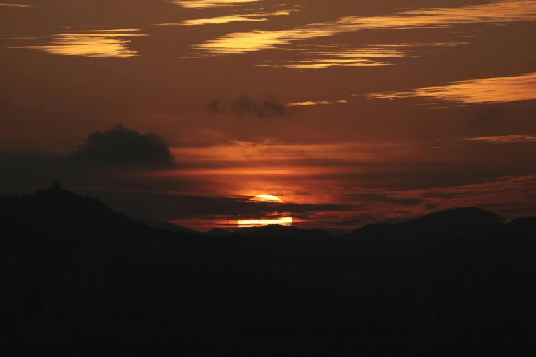 the setting sun is visible in the distance across hills