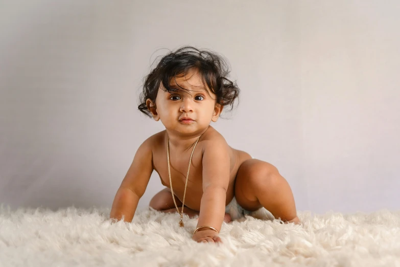 a small  in a brown shirt is sitting on a furry rug