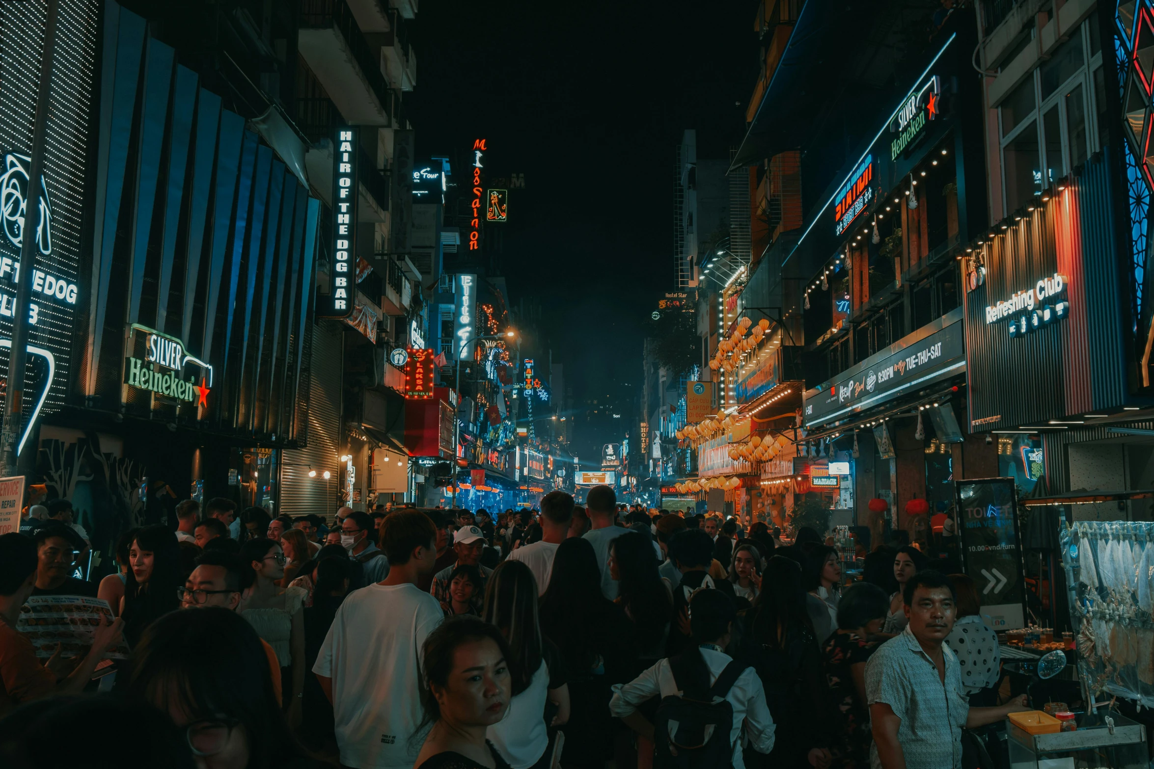 a city street with people walking on it at night