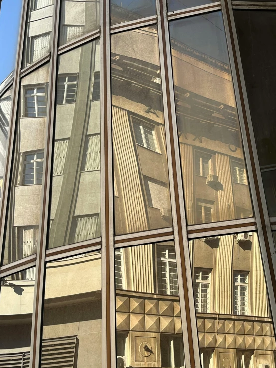 a tall building is reflected in the windows