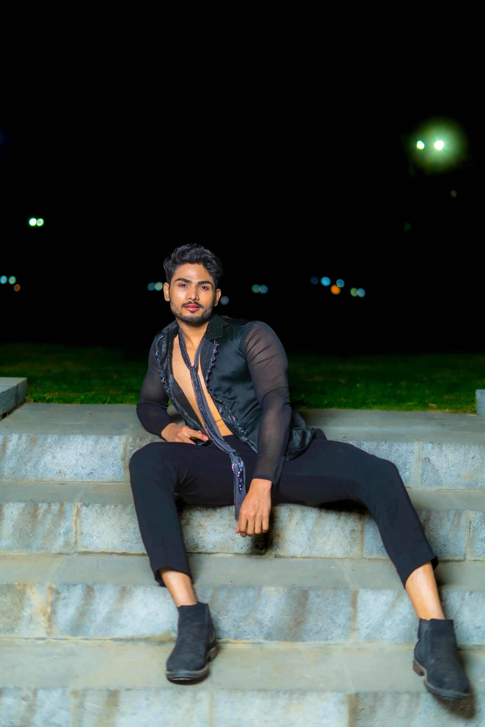 a man sitting on steps at night posing for a po