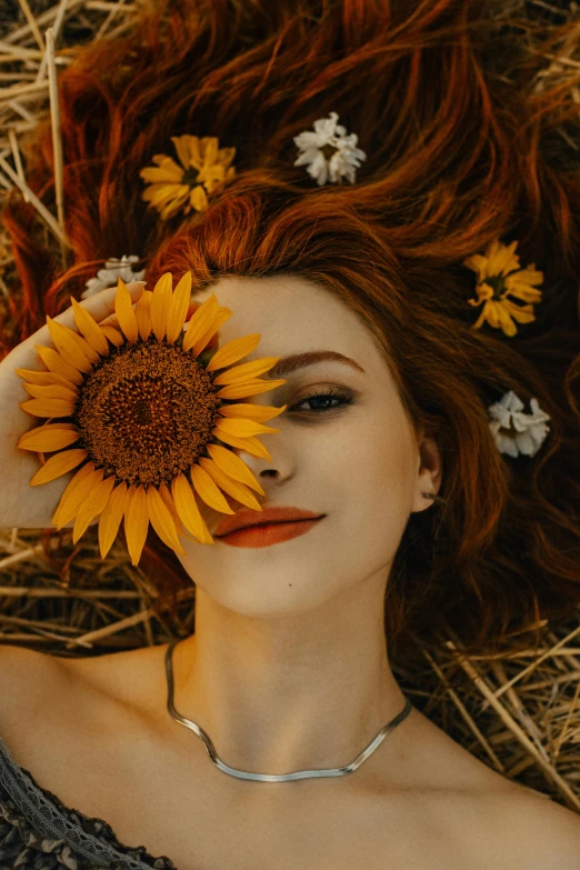 woman with sunflower in hair laying on straw