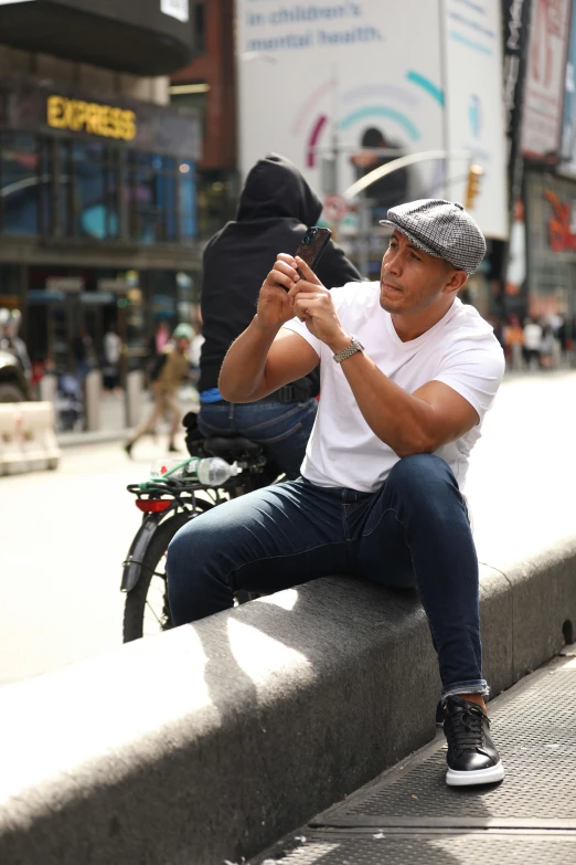 a man is sitting on the curb taking pictures