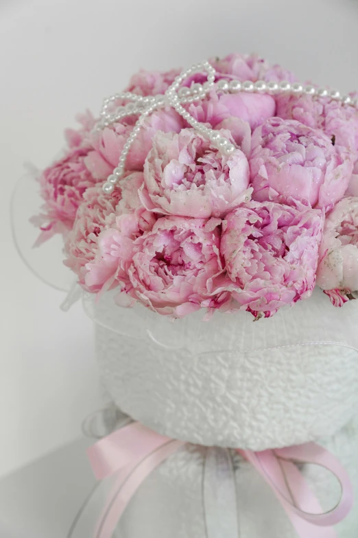 a pink flower arrangement in a white gift box