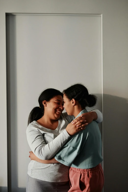 two women hug and look back in the picture