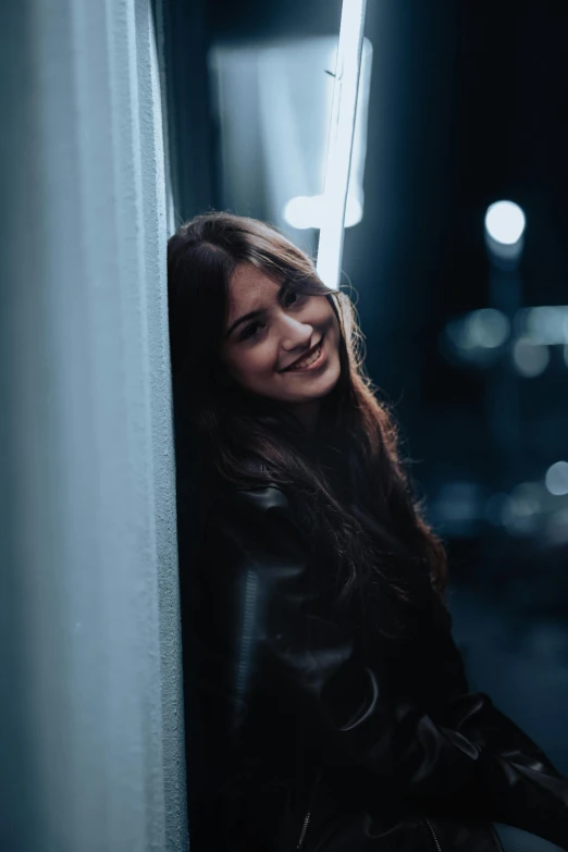 a girl is leaning against a wall smiling