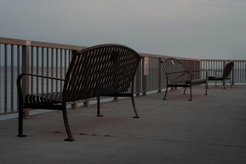 chairs on an empty pier near the ocean