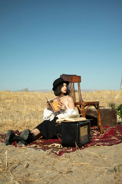 a girl sitting in a field on her cell phone