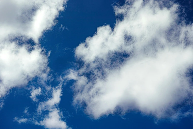 several clouds in the blue sky above a plane