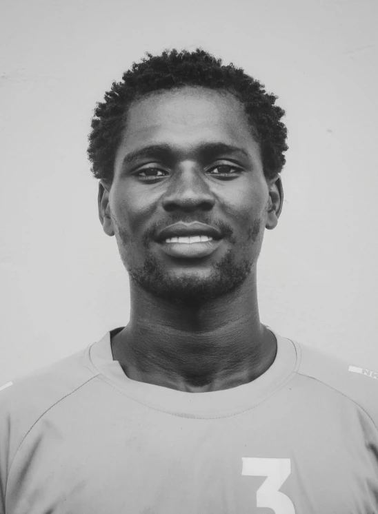 a smiling young man is posing in front of a wall