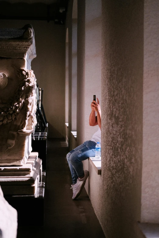 a woman holding a cell phone while sitting on a ledge