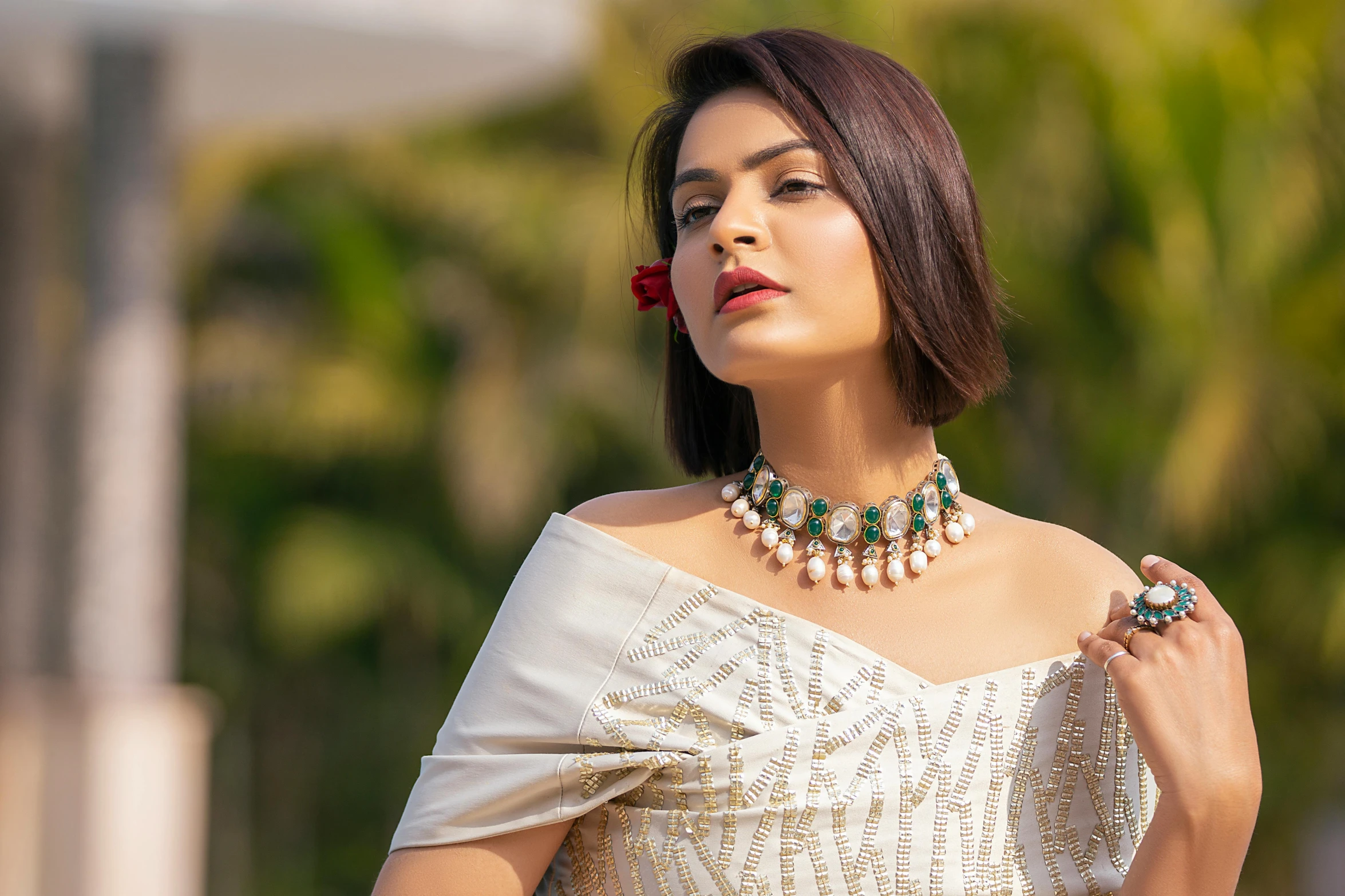 a beautiful woman with her head tilted down, in an off - shoulder top and pearl necklace