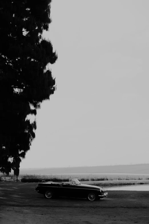 an old car parked near the ocean on a gloomy day