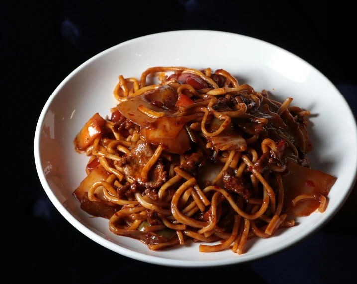 a white bowl filled with noodles on a black surface