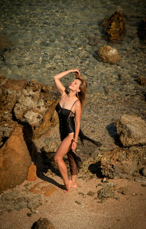 woman in a black bikini in water with rocks