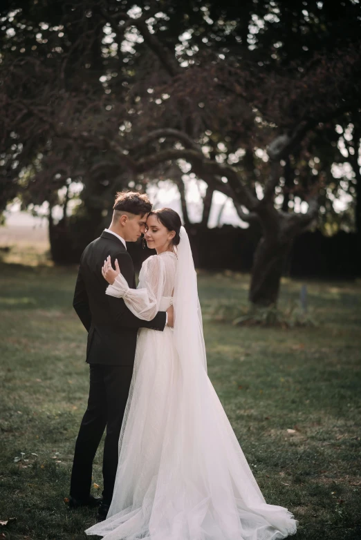 a bride and groom pose for a po in the park