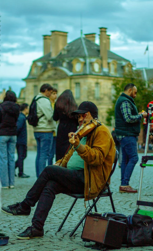 a man sitting on a chair playing the violin