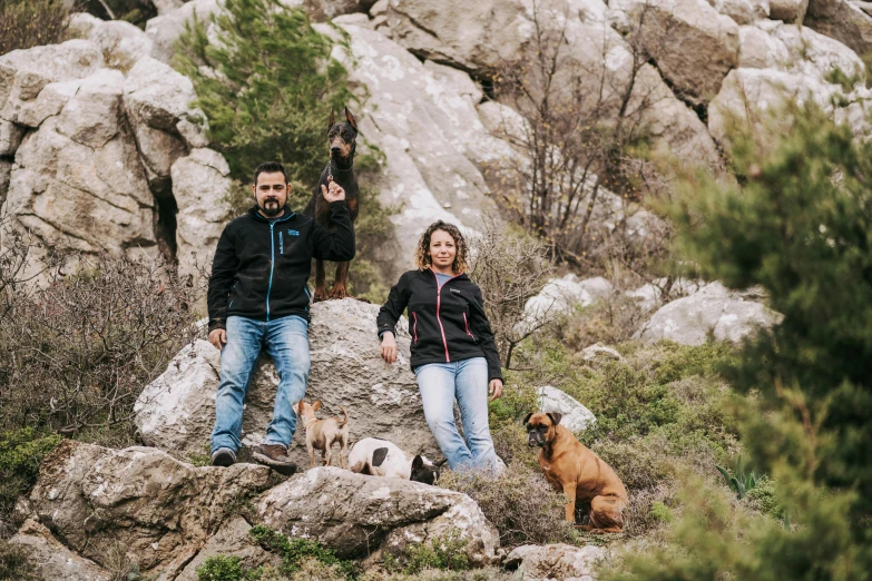 two people and dogs are standing on a rock