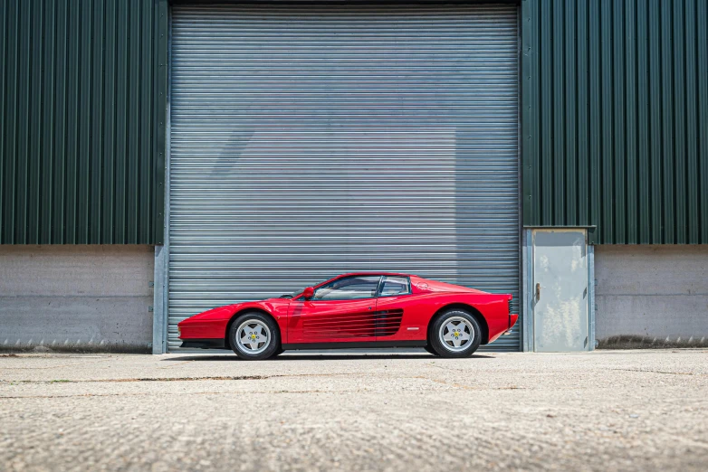 a red sports car parked in front of a large garage