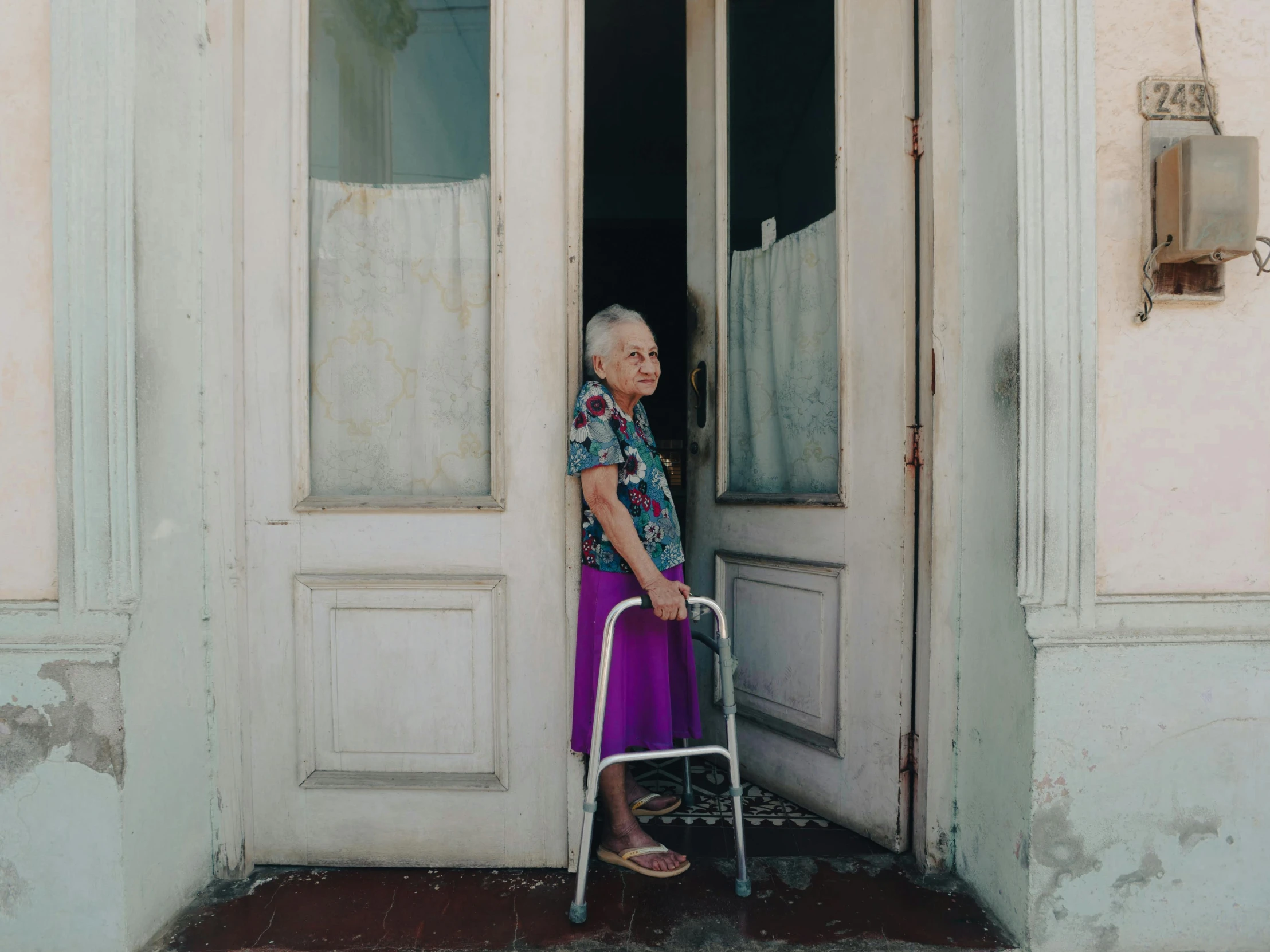 an elderly woman in wheelchair exiting a house