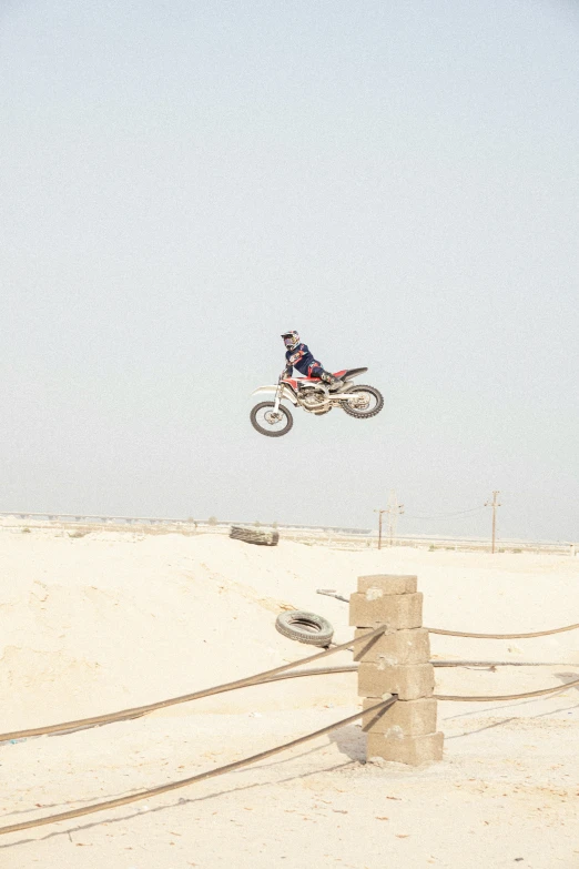 the motorcycle rider is airborne in midair over the beach